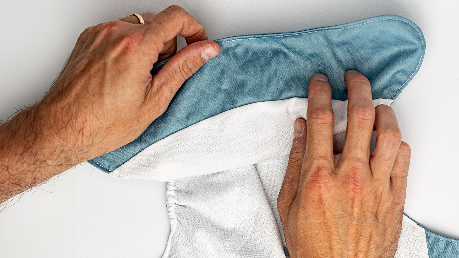 hands adjusting the interior of a modern cloth diaper along the tummy panel on a blue pocket style diaper for babies and toddlers