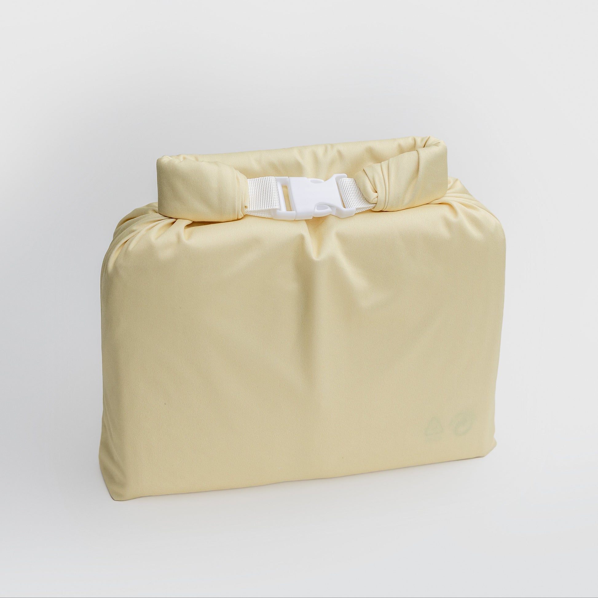 A pale yellow waterproof dry bag with a roll-top closure and white plastic buckle, shown on a clean light gray background.