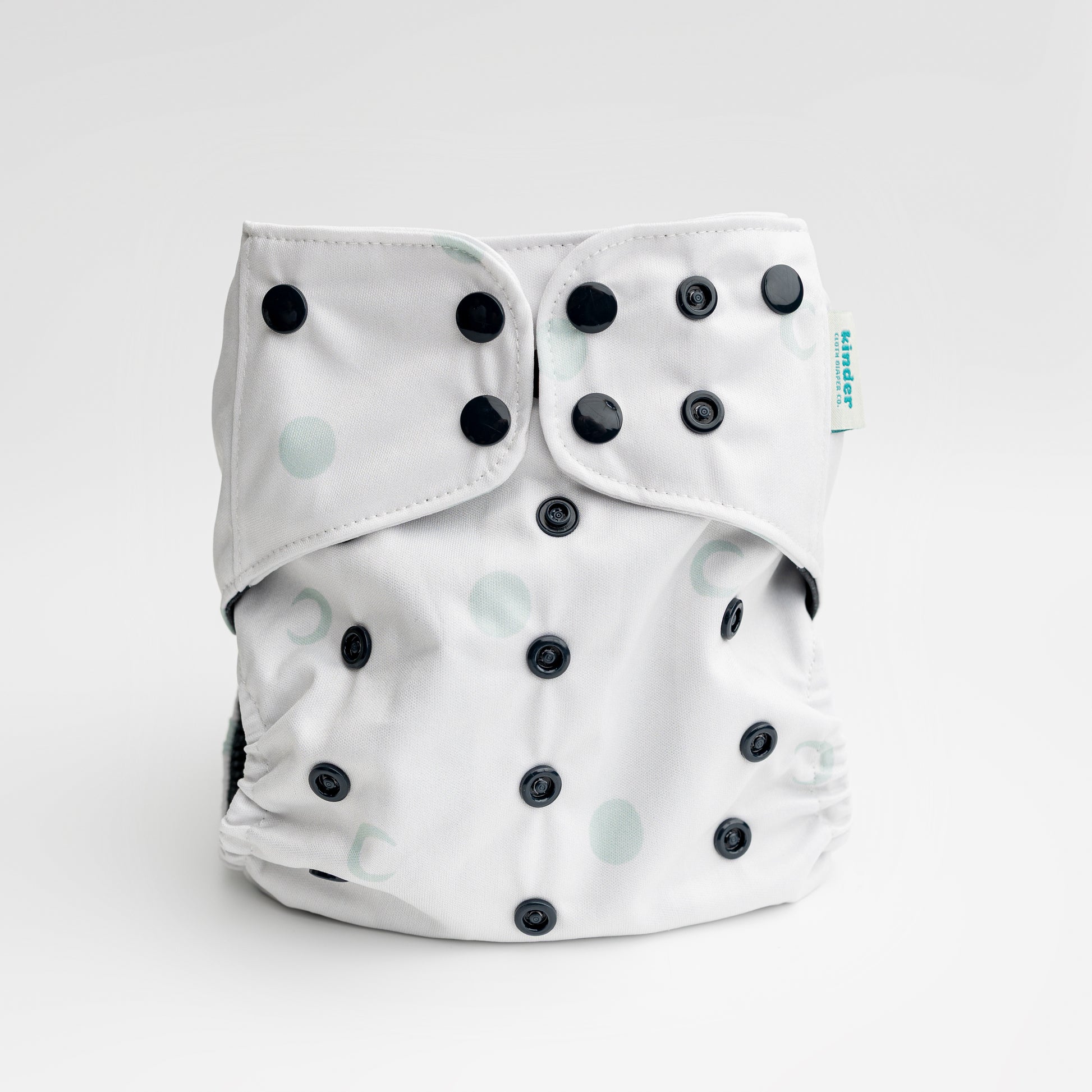 white cloth diaper with green moons and black snaps by kinder cloth diaper co with art by Malika Buttinger, one size fits most