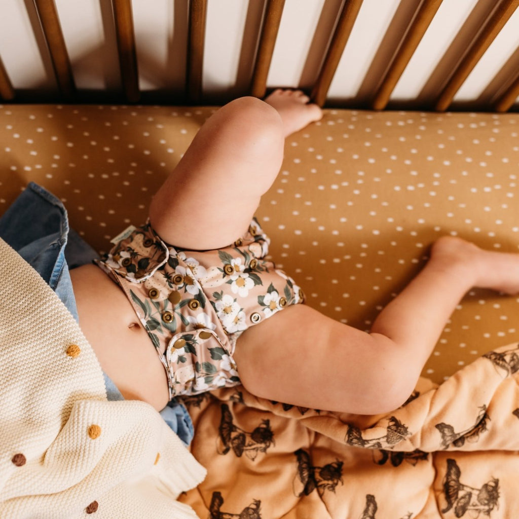 Baby in a crib with patterned cloth diaper
