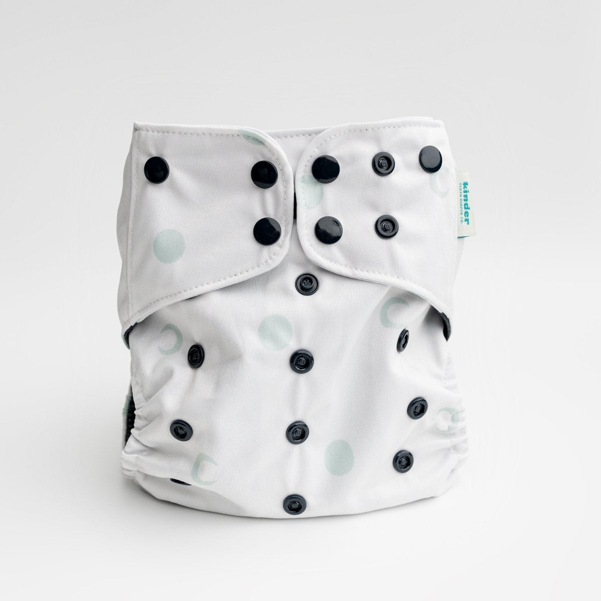 white cloth diaper with green moons and black snaps by kinder cloth diaper co with art by Malika Buttinger, one size fits most